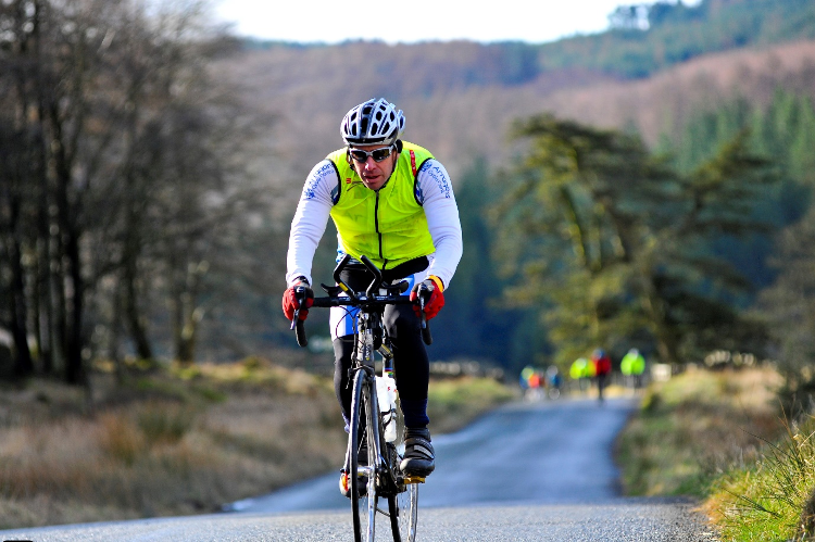 A man cycling in winter cycling clothes, including brightly coloured bib
